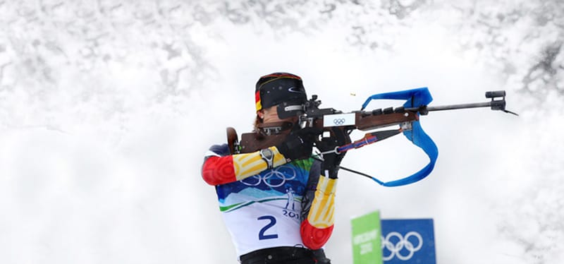 Biathlon race showing athletes on skis and preparing for the shooting range.